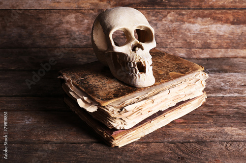 Still life with human skull and retro book on wooden background