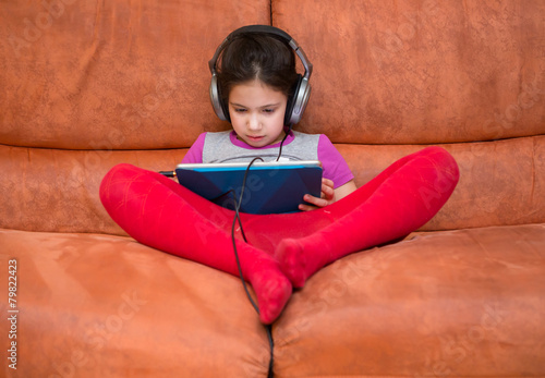 Little girl watching pad and headphones