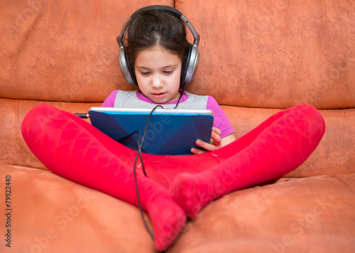Young girl watching tablet computer with headphones