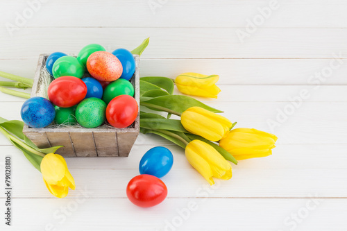 Easter eggs in basket and yellow tulips