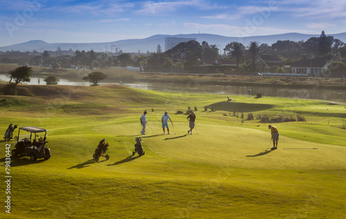 Golfers playing golf on a green lawn with a lagoon in background, Cape Town, South Africa  photo