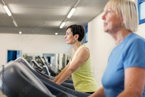 Two mature women are running on a treadmill