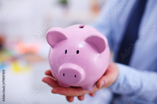 Businessman holding piggy box ,standing in office