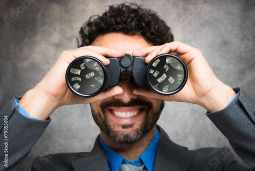 Canvas Print Businessman using binoculars, money reflected in the lens