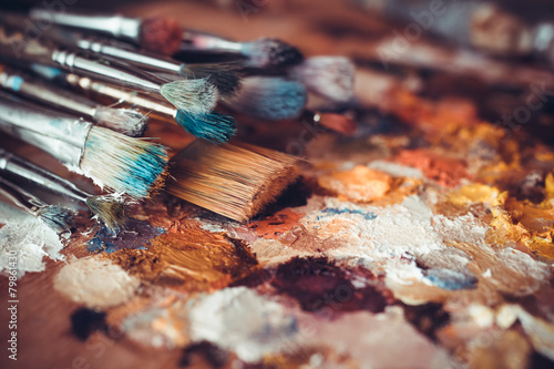 Paintbrushes closeup, artist palette and multicolor paint stains photo