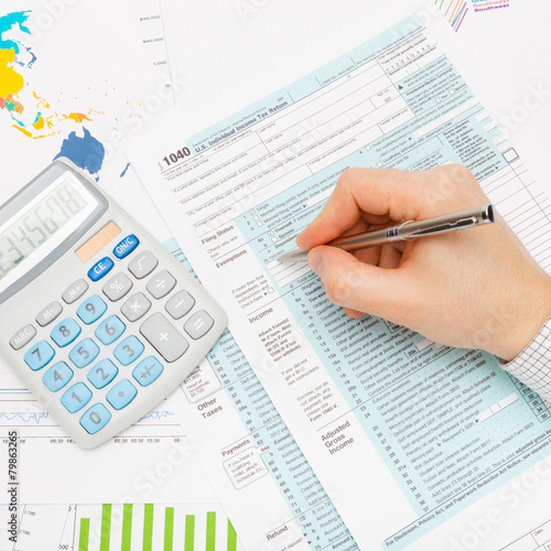 Male filling out 1040 US Tax Form with silver pen - studio shot