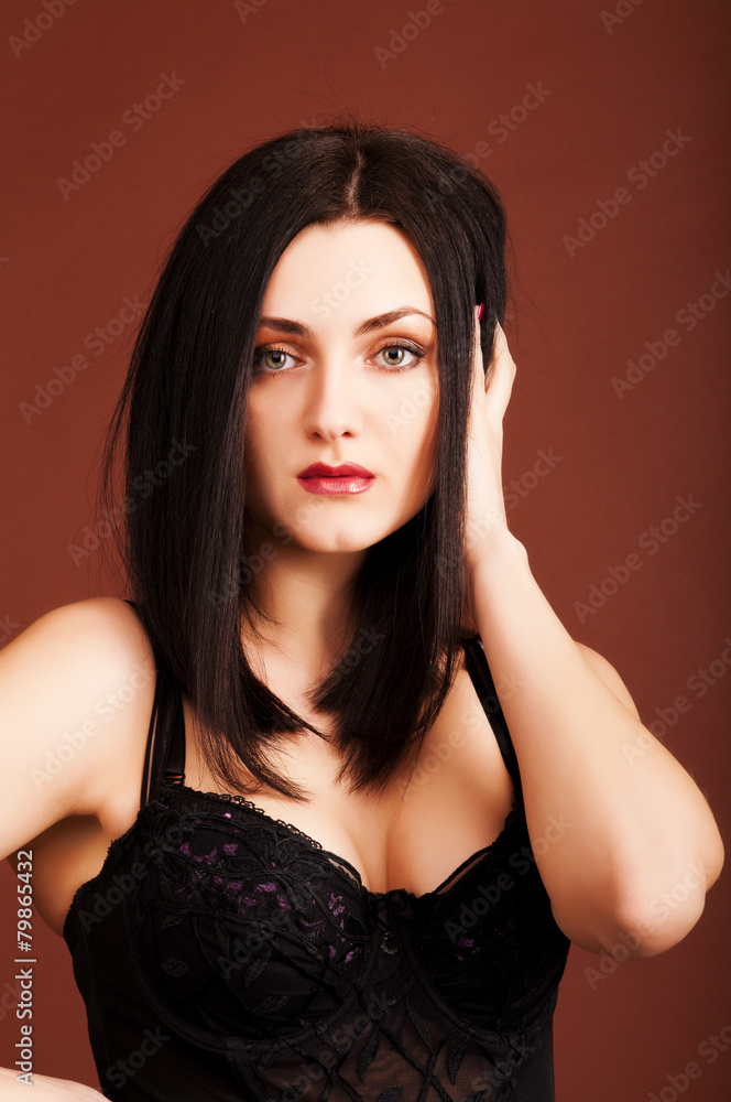 Brunette woman in black dress on the brown background Brunette woman in black dress on the brown background