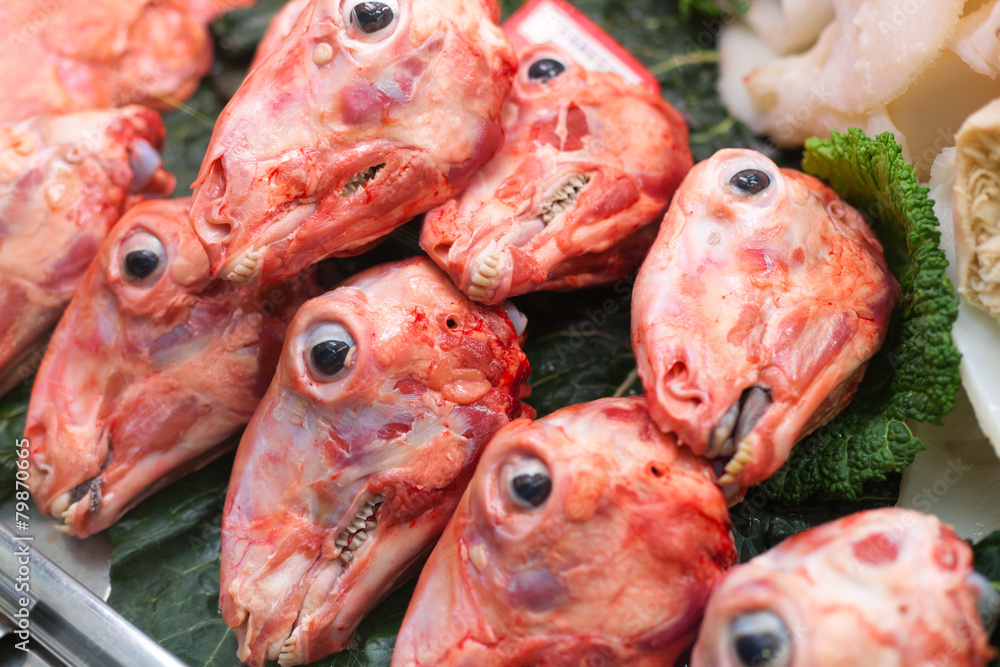 Skinned sheep's heads are lined up for sale at market stall, La