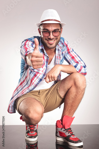 Happy young casual man showing the thumbs up gesture