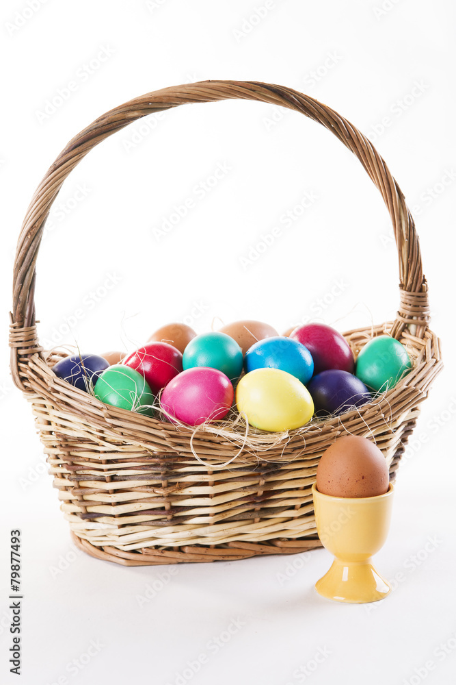 Wicker basket with colored eggs on a white background
