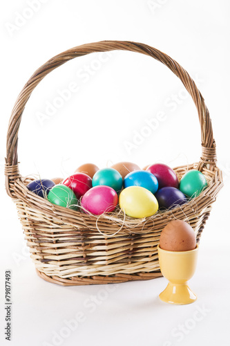 Wicker basket with colored eggs on a white background