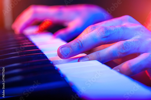 hands of musician playing keyboard in concert with shallow depth