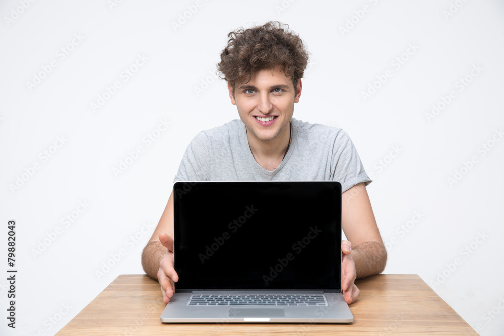 Cheerful man sitting at the table and showing laptop screen Cheerful man sitting at the table and showing laptop screen