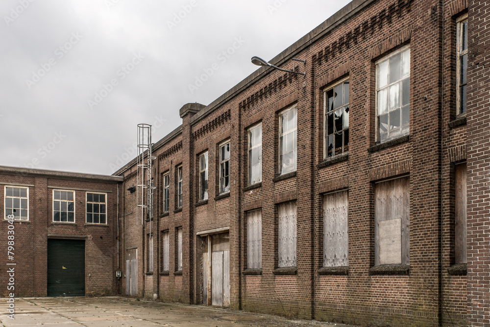 brick facade with broken windows of an old abandoned factory