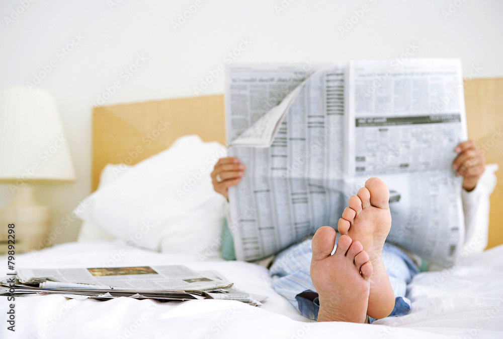 Fototapeta premium man reading newspaper in bed