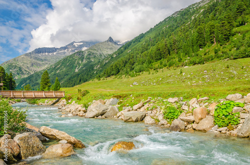Mountain stream, green meadows and peaks of the Alps, Austria