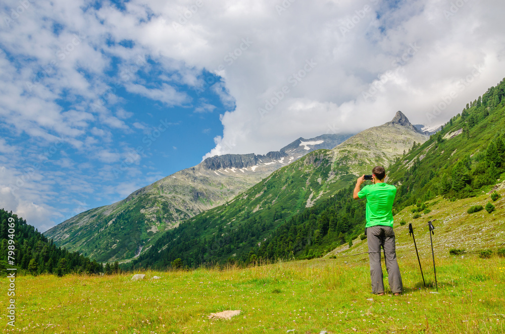 Young mountaineer taking a photo of alpine landscape, Alps
