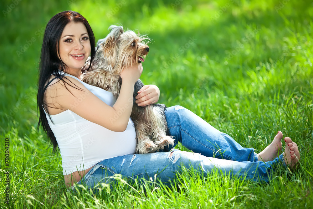 Pregnant woman are playing with dog on grass Pregnant woman are playing with dog on grass