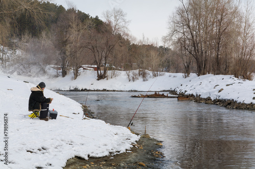 fisherman with a fishing rod on the river in winter