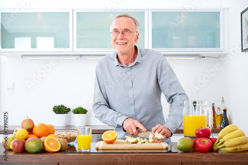 Mature man in the kitchen prepare fruits for breakfast. VI