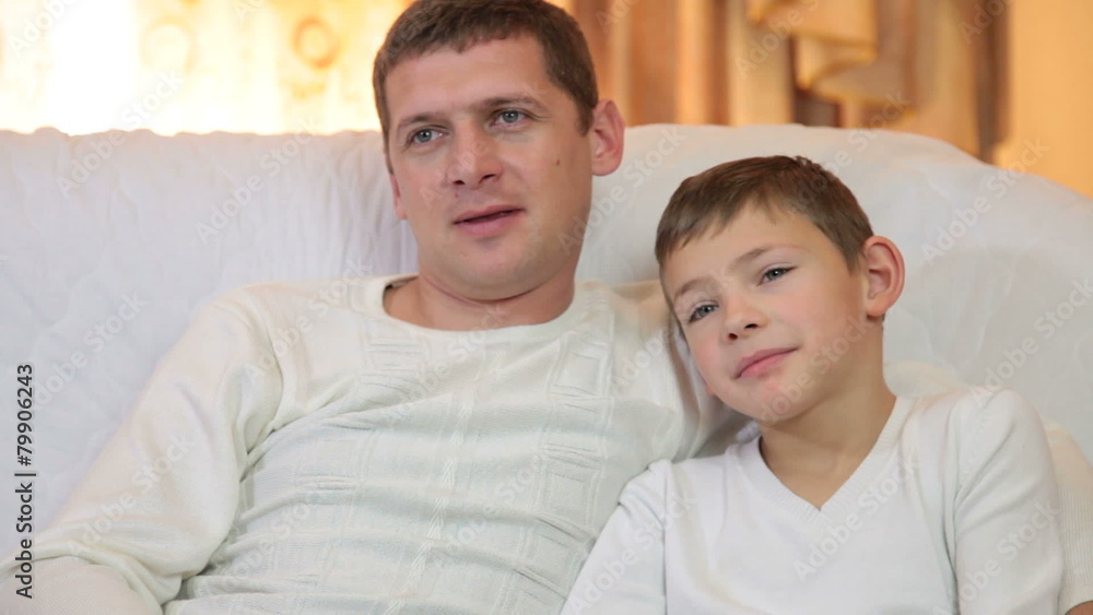 Father and son watching television together Father and son watching television together