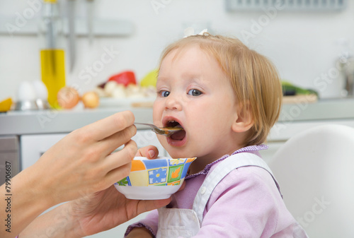 mother feeding baby in the kitchen