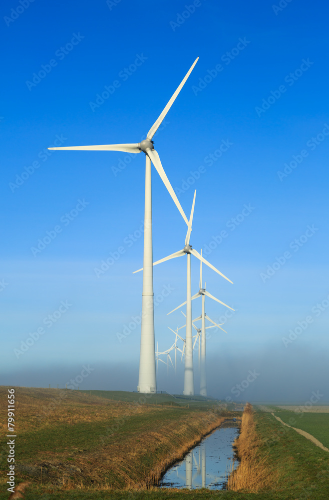 Wind turbines generating sustainable energy on a foggy morning.