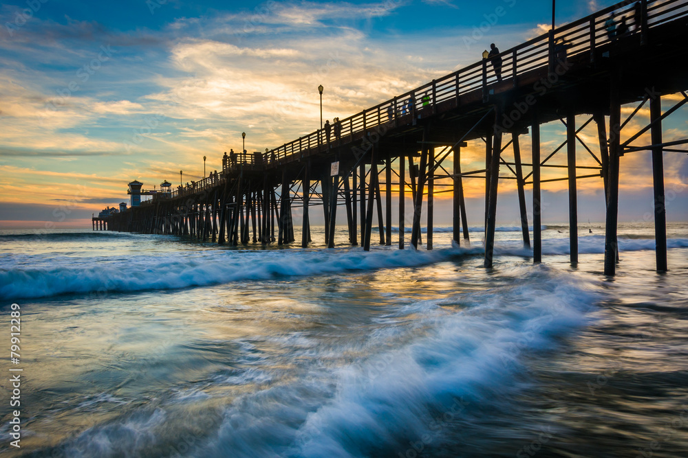 The pier and waves in the Pacific Ocean at sunset, in Oceanside,