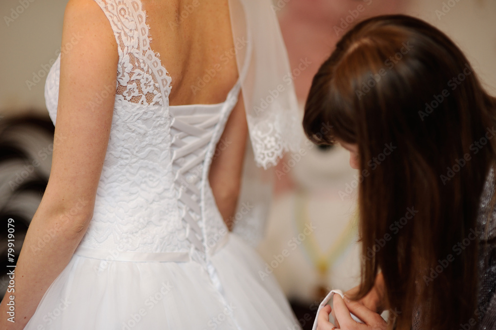 bridesmaid helps the bride lace corset wedding dress