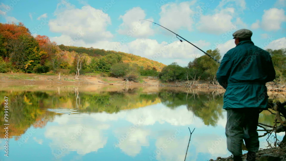 man with fishing rod fishing on the lake in the autumn forest man with fishing rod fishing on the lake in the autumn forest