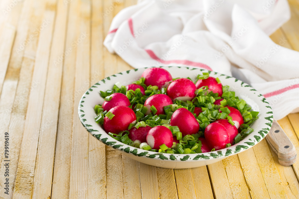 Bowl of red radishes and green onions on a wooden background Bowl of red radishes and green onions on a wooden background