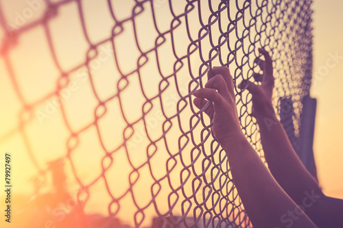 Fotografie Hand holding on chain link fence