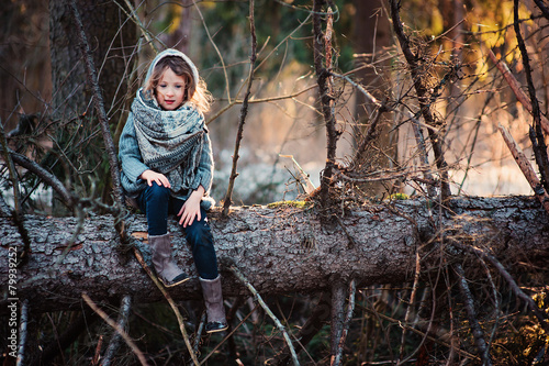 child girl sit on old pine tree in early spring forest