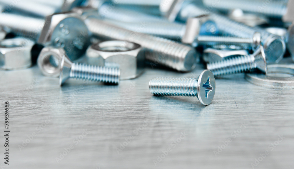 Nuts, screws and bolts on scratched metal background. Nuts, screws and bolts on scratched metal background.