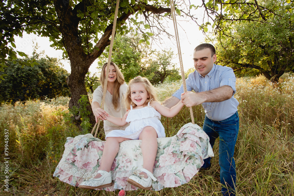 Fototapeta premium Родители катают дочь на качеле