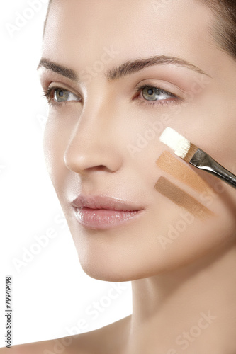 Beautiful model applying foundation with a brush