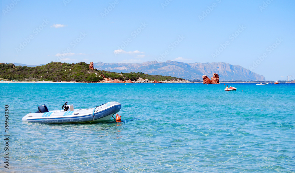 white rubber boat in the clear blue sea, mountains in background