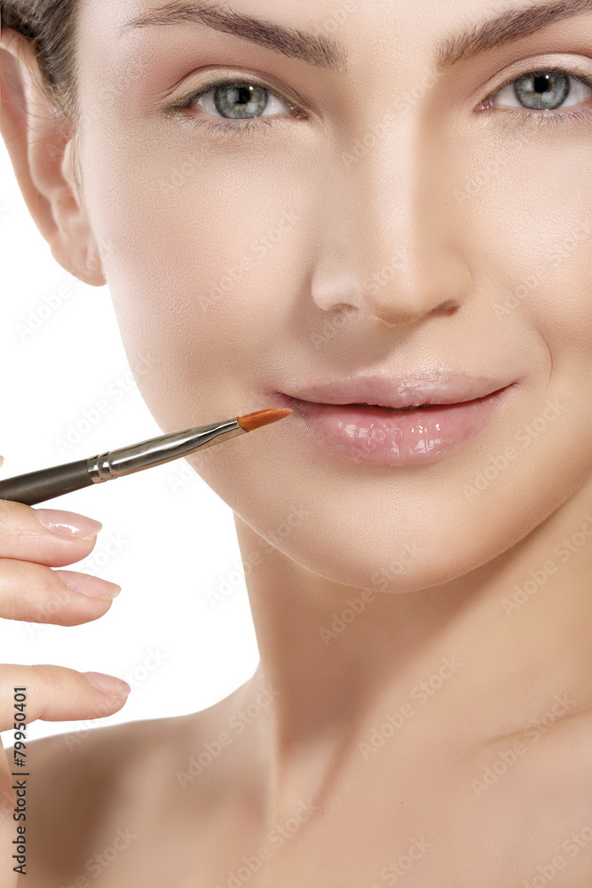 Beautiful model applying lip gloss with a brush Beautiful model applying lip gloss with a brush