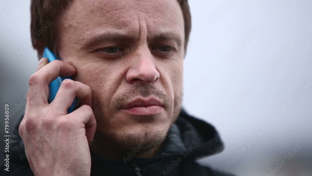 Adult serious man talking on the phone outdoors in winter Adult serious man talking on the phone outdoors in winter