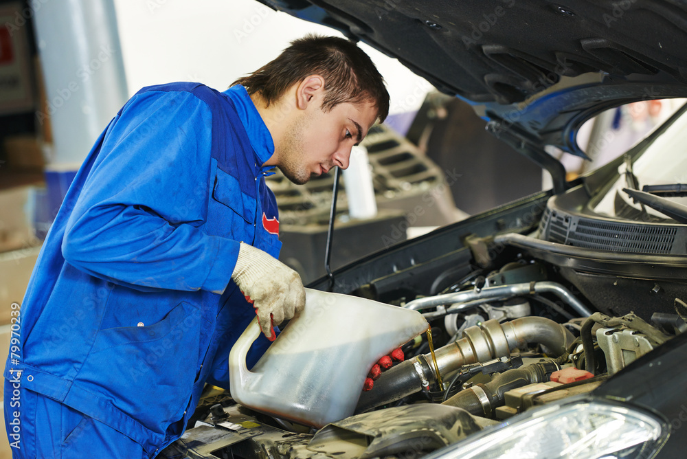 car mechanic pouring oil into motor engine car mechanic pouring oil into motor engine