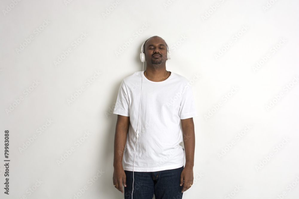 Fototapeta premium Indian young man with headphone on plain background.
