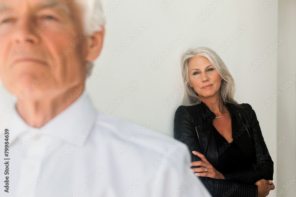Mature woman looking at her husband standing in the foreground Mature woman looking at her husband standing in the foreground
