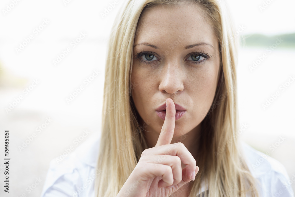 Portrait of young woman with finger on her mouth Portrait of young woman with finger on her mouth