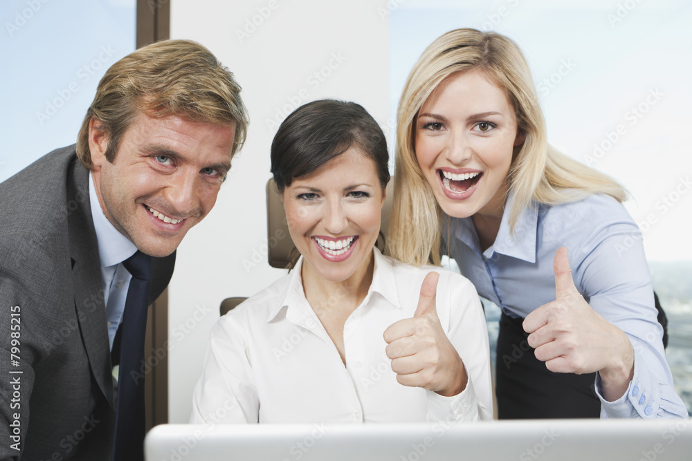 Germany, Frankfurt, Business people using laptop and showing thumbs up Germany, Frankfurt, Business people using laptop and showing thumbs up