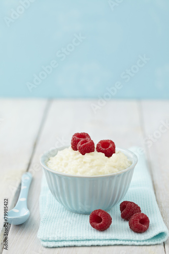 Bowl of milk rice pudding with raspberries on table photo