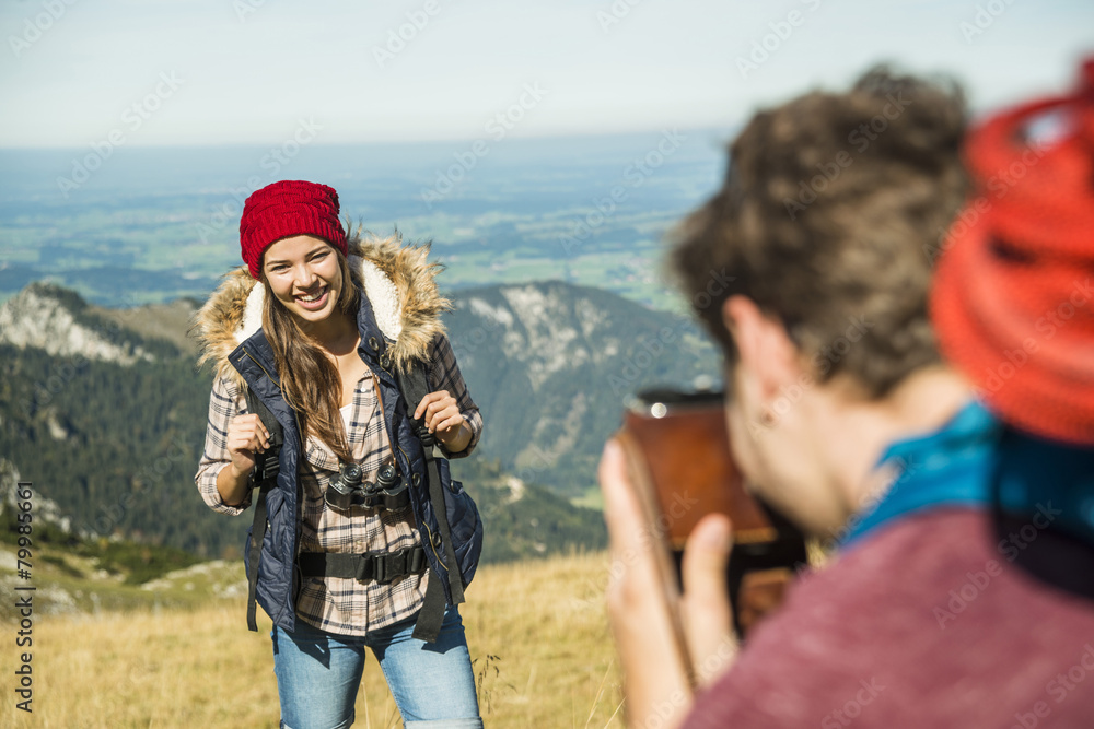 Austria, Tyrol, Tannheimer Tal, young man taking picture of girlfriend on alpine meadow Austria, Tyrol, Tannheimer Tal, young man taking picture of girlfriend on alpine meadow