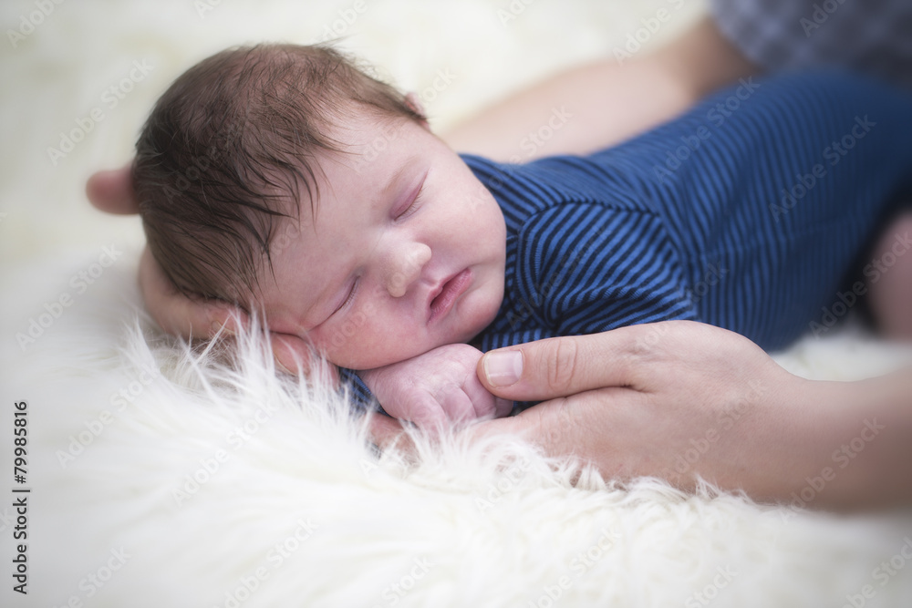 Father's hands holding sleeping baby boy