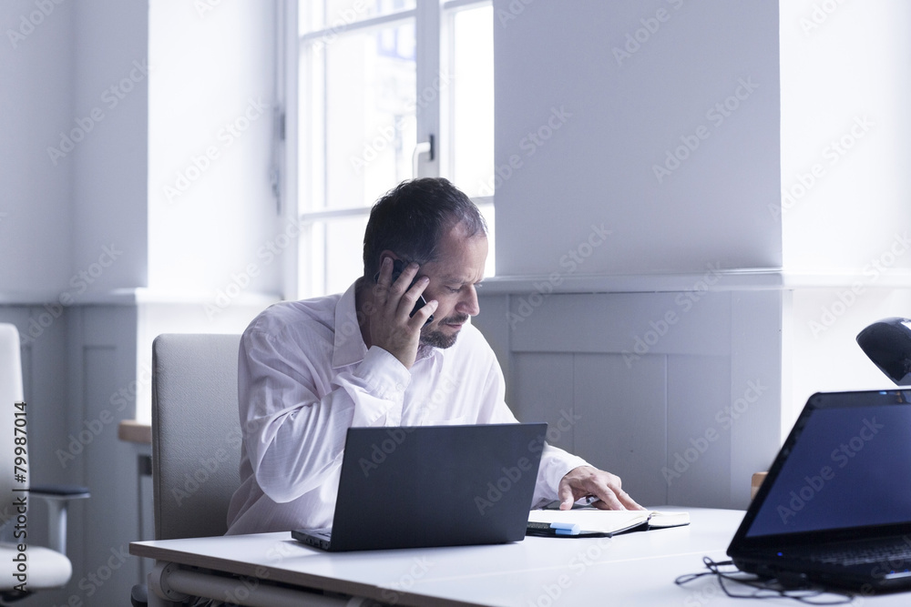 Businessman telephoning with smartphone at his desk Businessman telephoning with smartphone at his desk