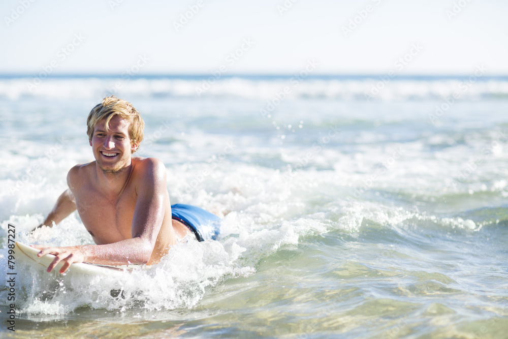 Happy young man lying on surfboard in the sea Happy young man lying on surfboard in the sea