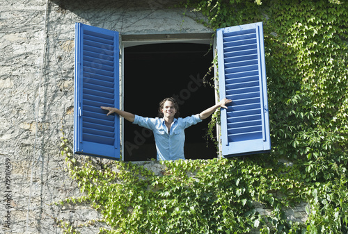 Italy, Tuscany, Young man leaning on window with shutters